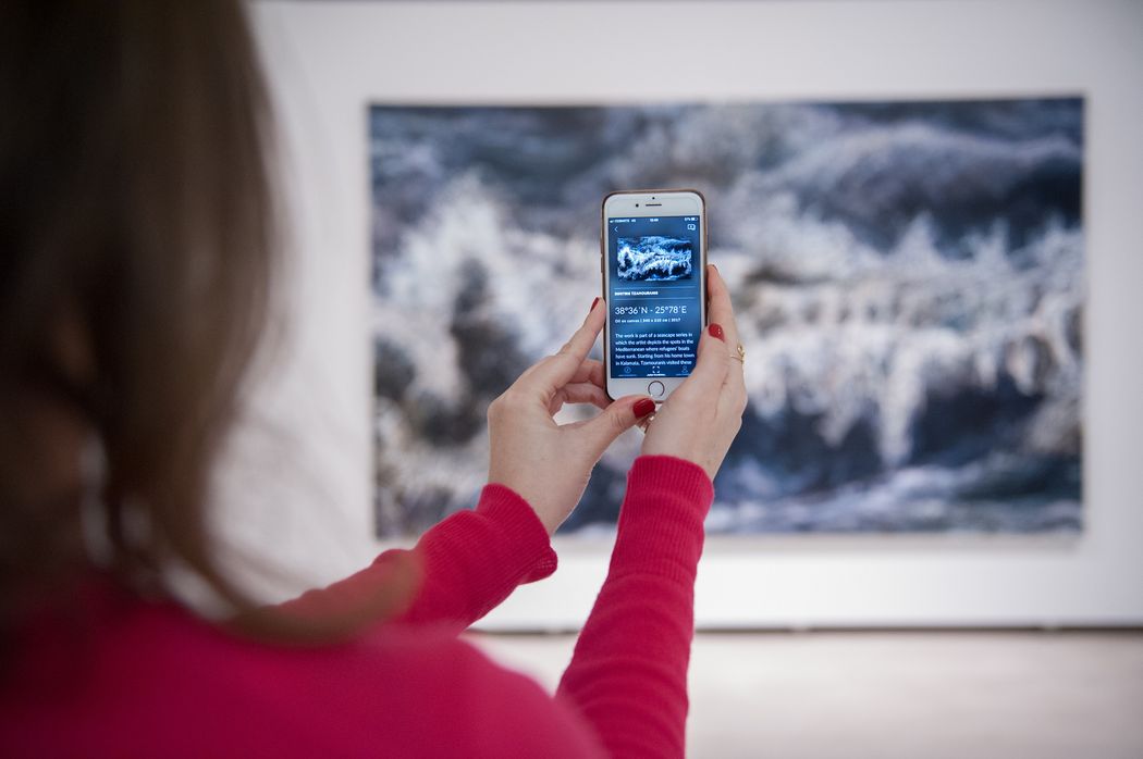 A person holding a phone up to a painting in a gallery and using the Smartify app to scan artwork